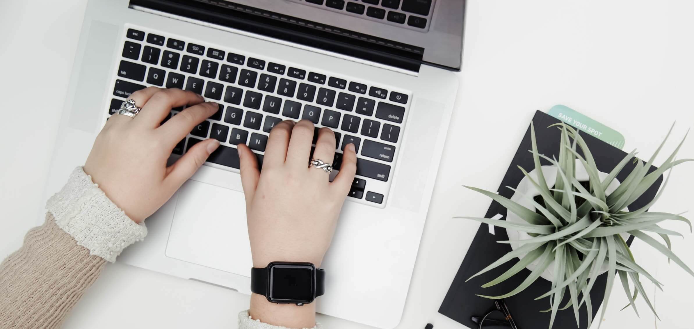 Top down view of laptop with womens hands on keyboard